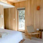 Bright minimalist bedroom featuring wooden walls and flooring in Catskill, NY.