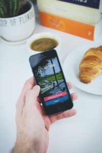 airbnb, app, apple, book, coffee, croissant, hand, holding, ios, iphone, mobile, phone, table, white, airbnb, airbnb, airbnb, airbnb, airbnb