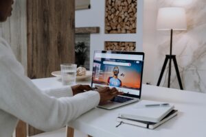 Faceless person using a laptop with online content in a cozy modern setting.